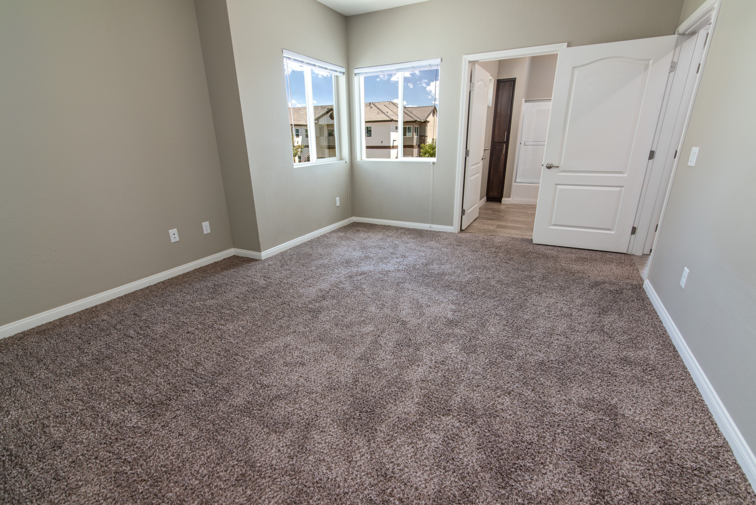 After image of the same master bedroom with corrected lighting, where the previously yellow hue of the bathroom and hall has been eliminated. The colors are now natural and pleasing, with crisp but not exaggerated details. The views through the windows are clear and realistic, making the room highly inviting and creating a space that exclaims, “I want to live here.”