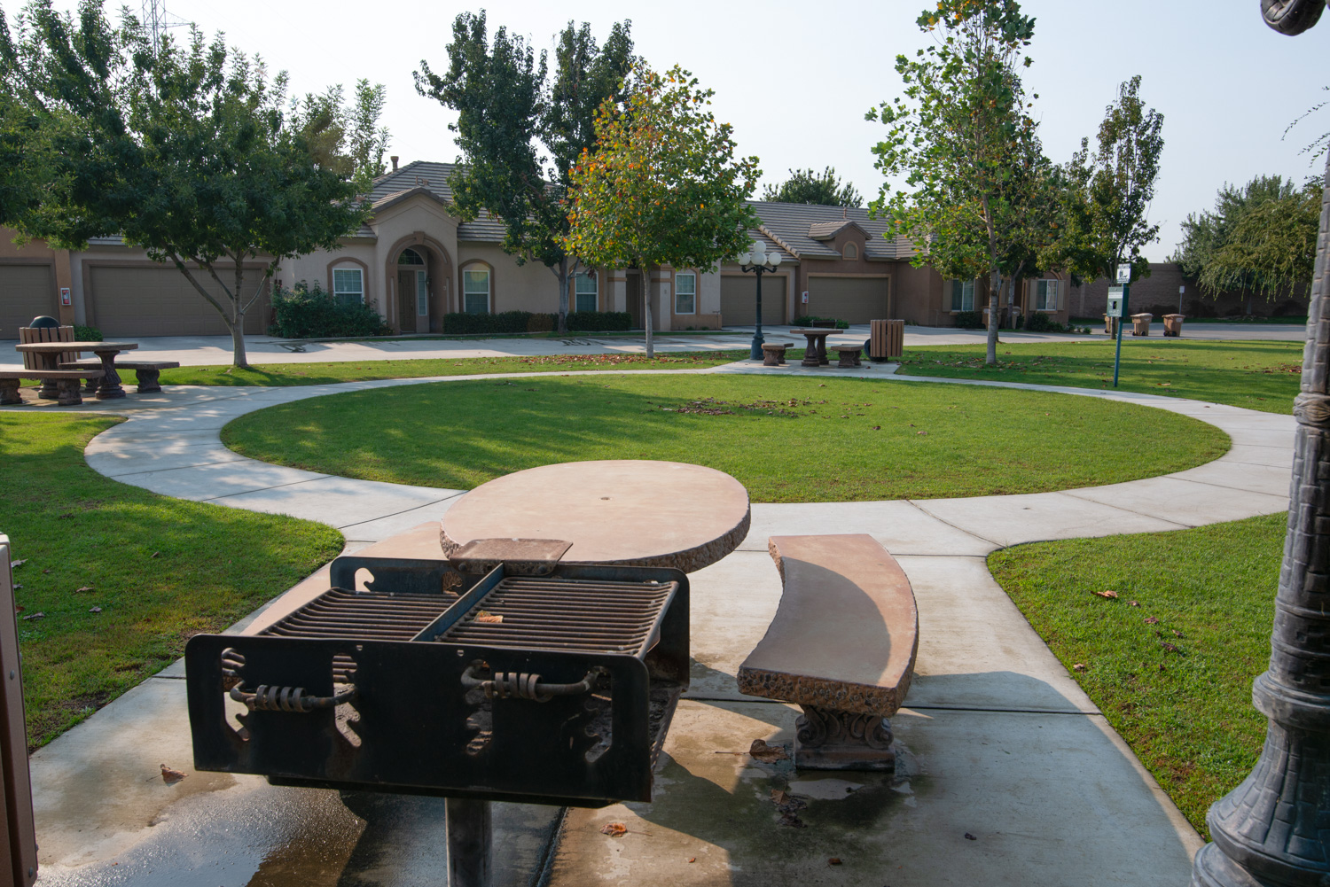 A before image of a community barbecue area showing water stains and standing water, along with leaves and yellow patches on otherwise nice grass, depicting common outdoor challenges.