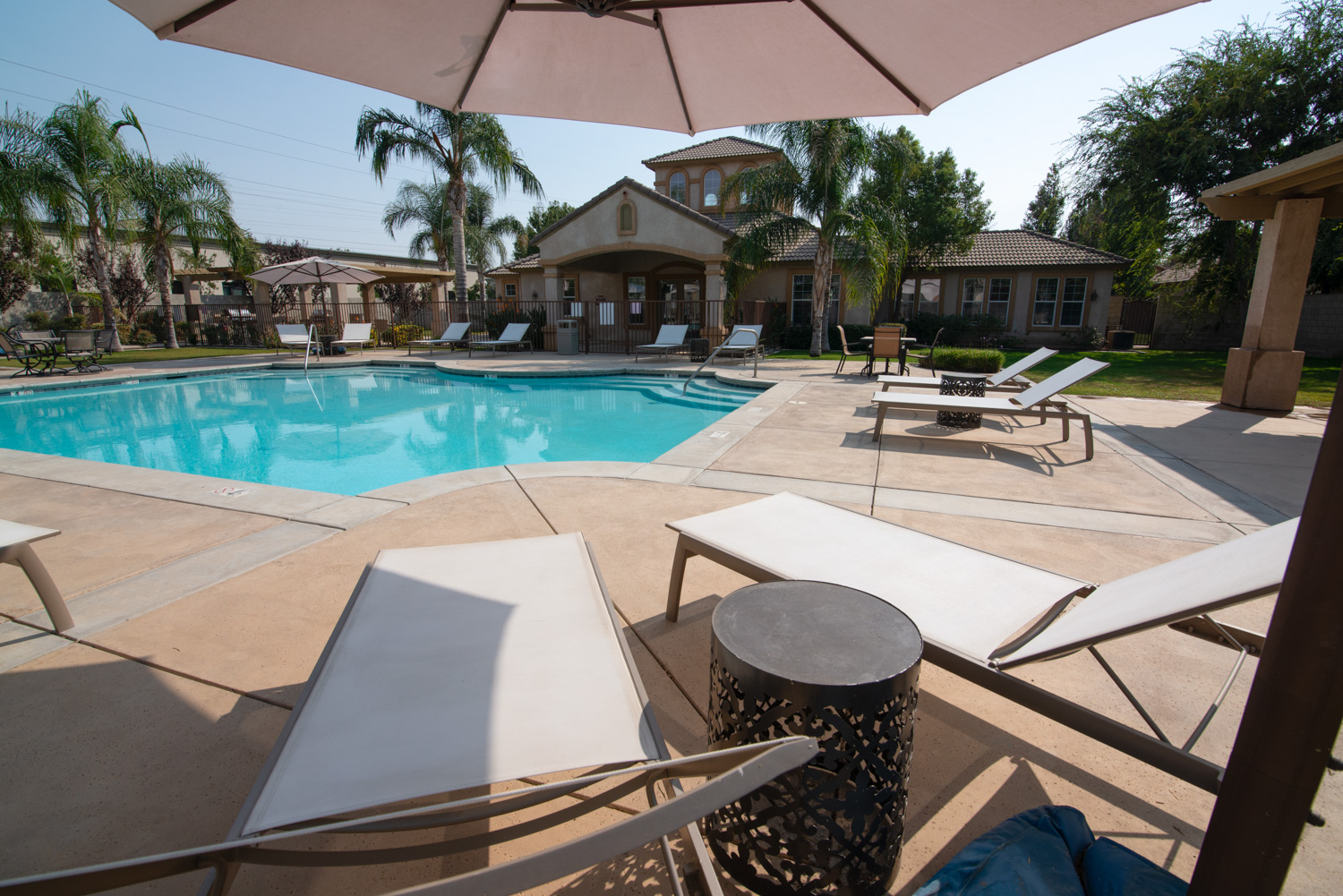 A before image of a luxury apartment showcasing some typical issues even in upscale settings, such as bare patches on the grass and shadows that obscure important details of the exterior.