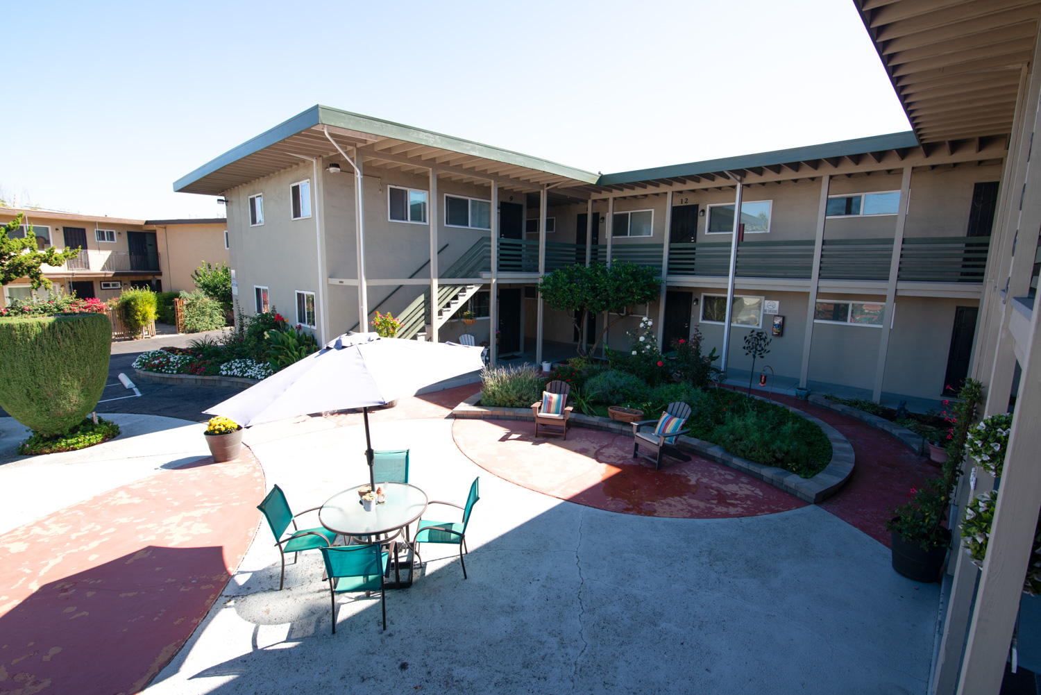 A before image of a smaller apartment's courtyard displaying signs of wear such as cracked and discolored sidewalks and areas of chipped paint, illustrating typical minor issues found in many communities.