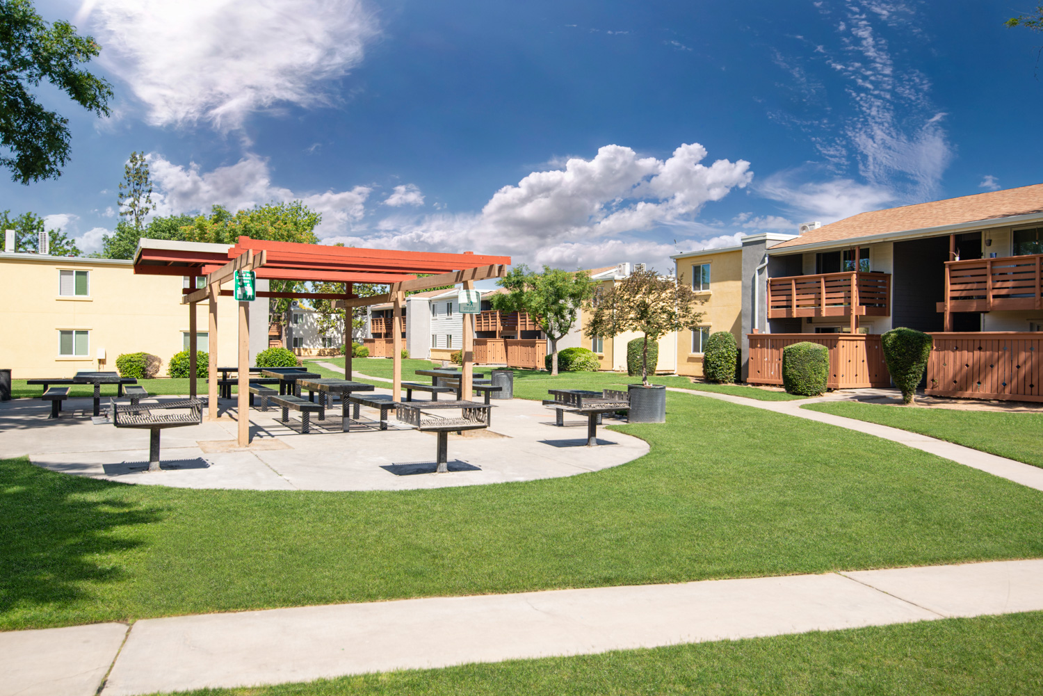 An after image of an apartment community featuring perfect grass, cleaned sidewalks, and a dramatic sky. The enriched colors throughout the scene enhance its appeal, making it look more inviting to live in.