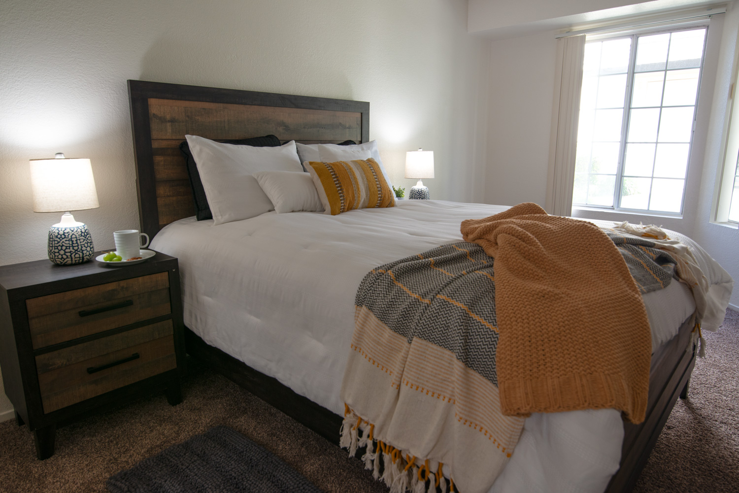 A before image of a staged apartment bedroom, showing shadows that obscure important details and dull colors throughout the room.