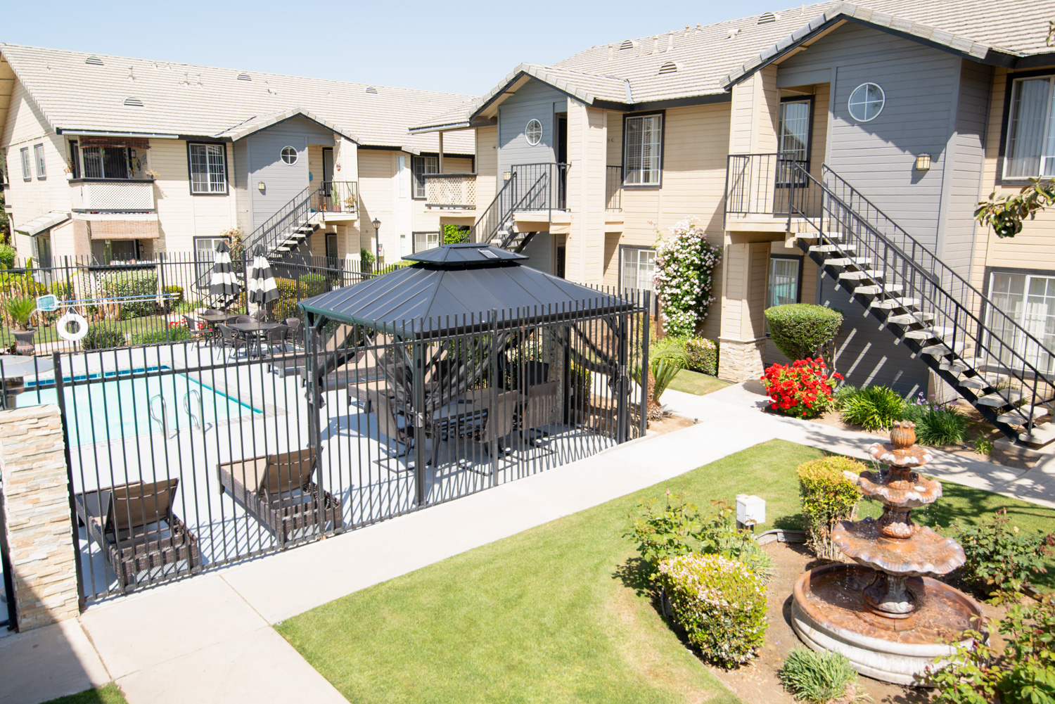 A before photograph of an apartment community with a faded sky and a lawn that is not perfectly green. The image shows typical community flaws and lacks vivid colors.